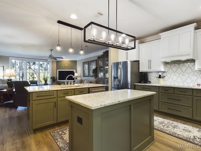 kitchen featuring white cabinetry, stainless steel appliances, decorative light fixtures, and a kitchen island