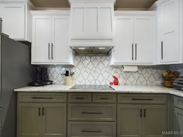 kitchen featuring black electric stovetop, white cabinets, tasteful backsplash, and premium range hood