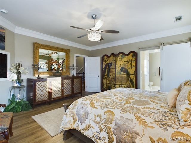 bedroom with ensuite bathroom, a barn door, dark hardwood / wood-style flooring, ceiling fan, and crown molding