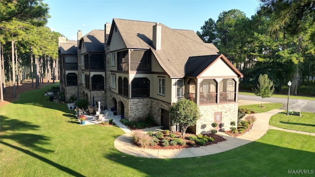 rear view of house featuring a lawn and a balcony