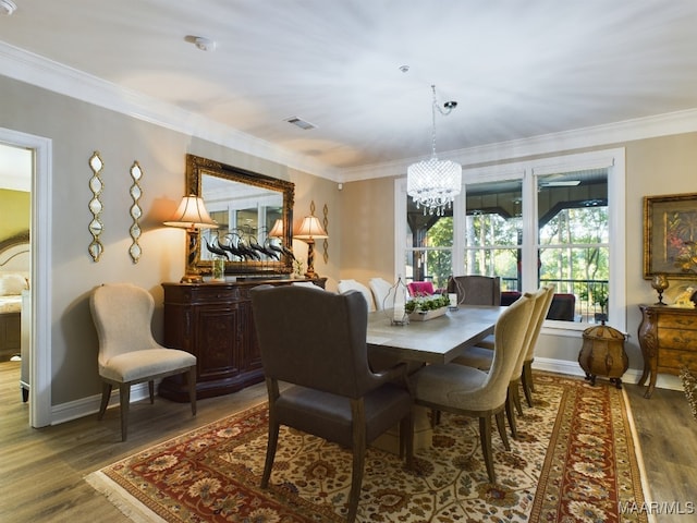 dining area with a notable chandelier, a healthy amount of sunlight, wood-type flooring, and ornamental molding