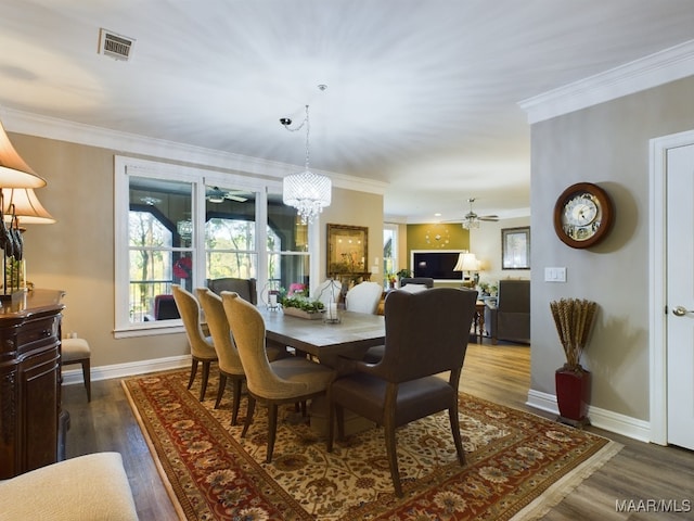 dining space featuring crown molding, dark hardwood / wood-style flooring, and ceiling fan with notable chandelier