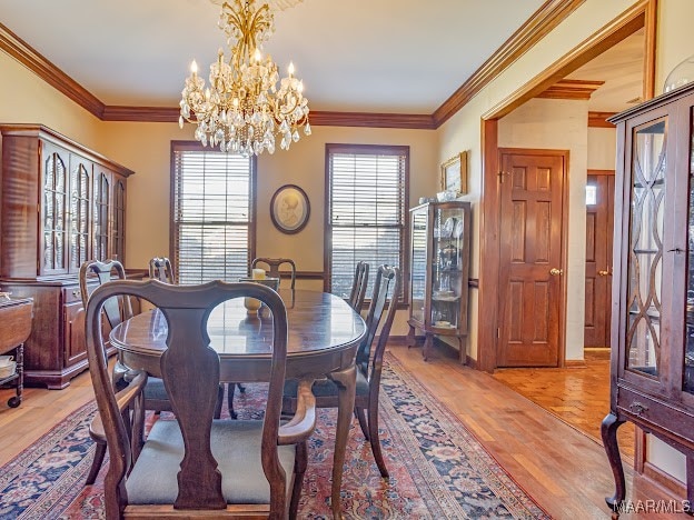 dining space with crown molding, a wealth of natural light, an inviting chandelier, and light hardwood / wood-style floors