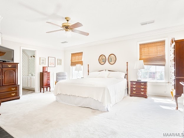 carpeted bedroom with ornamental molding, ensuite bath, and ceiling fan