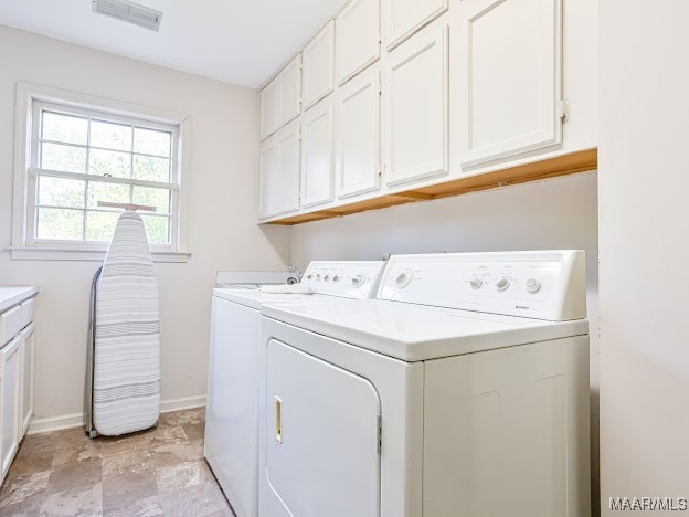 laundry room featuring washer and clothes dryer and cabinets