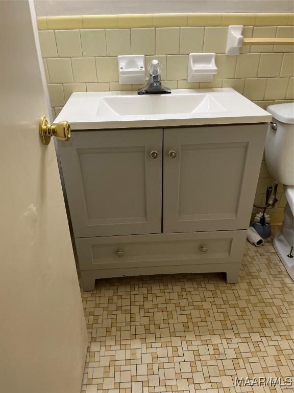 bathroom with vanity, tile walls, and toilet