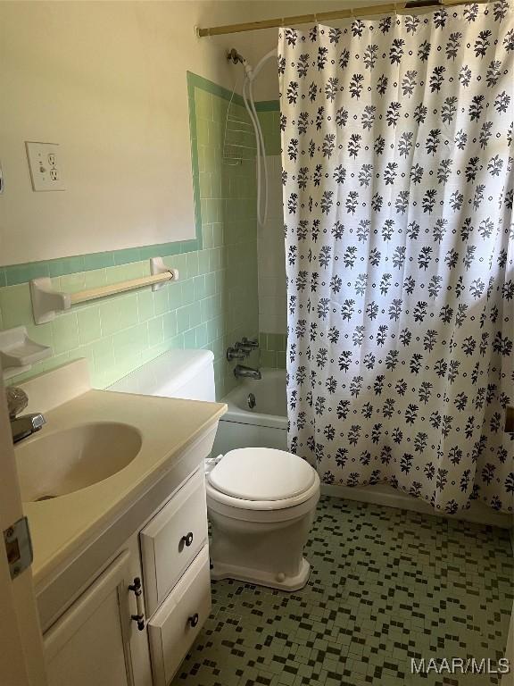 full bathroom featuring tiled shower / bath, tile walls, vanity, and toilet