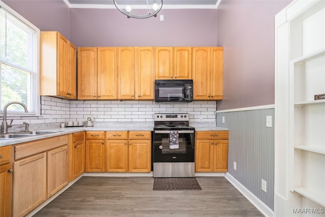 kitchen with sink, wooden walls, stainless steel range with electric cooktop, light wood-type flooring, and crown molding