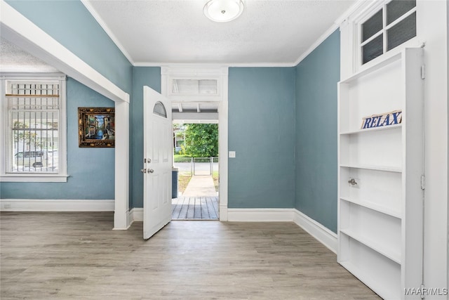 foyer featuring light hardwood / wood-style floors, crown molding, and a textured ceiling