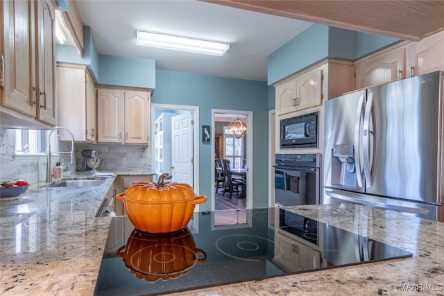 kitchen with backsplash, light brown cabinets, a sink, light stone countertops, and black appliances