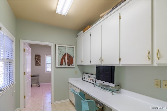 office space featuring light tile patterned floors, built in desk, and baseboards