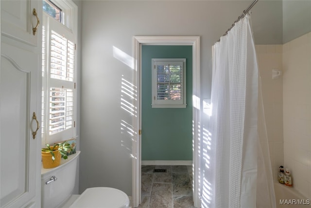 bathroom with toilet, curtained shower, and a wealth of natural light