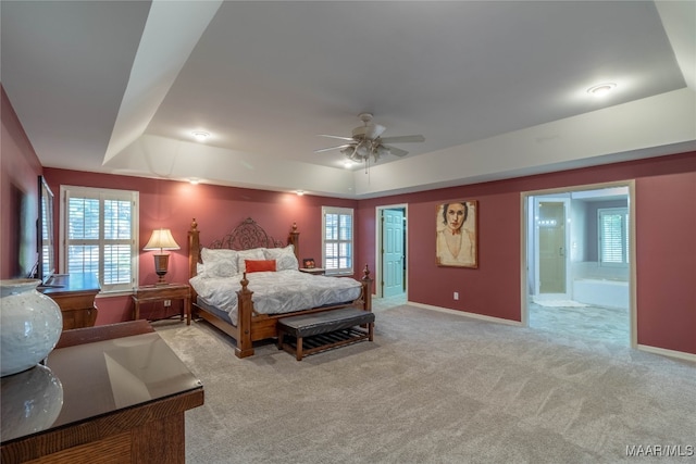 carpeted bedroom with a tray ceiling, a ceiling fan, and baseboards