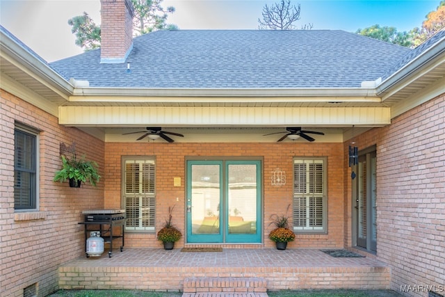 entrance to property with ceiling fan, brick siding, roof with shingles, and a chimney