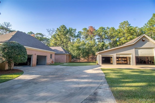 view of home's exterior featuring a garage, a shingled roof, concrete driveway, a lawn, and an outbuilding