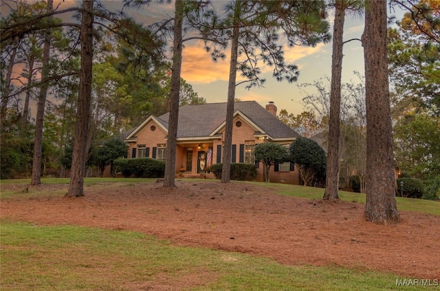 view of front facade with a front yard, brick siding, and a chimney