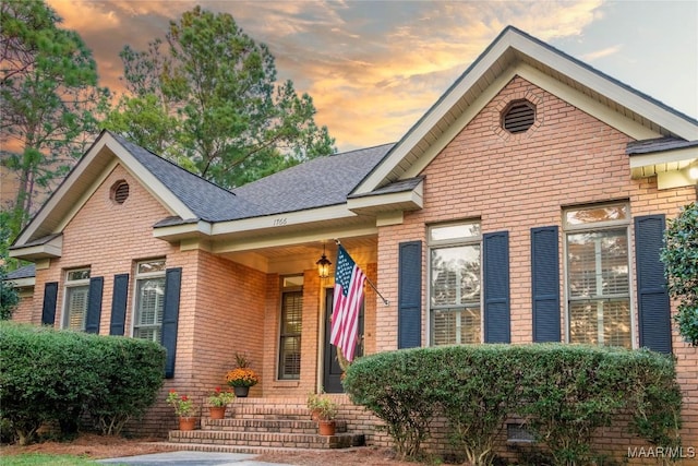 view of front of house with brick siding and a shingled roof