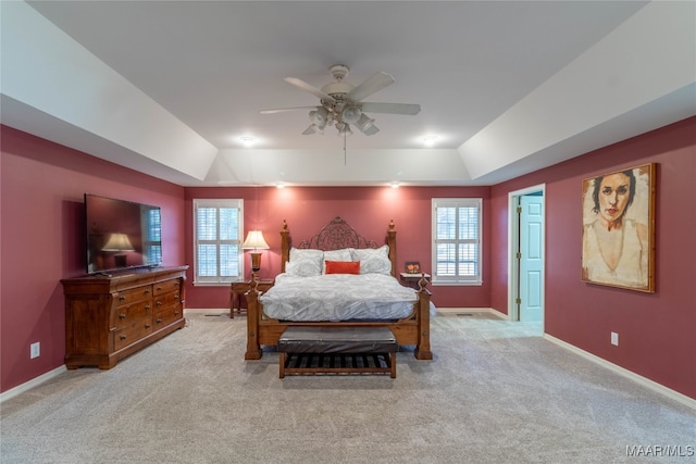 bedroom with carpet, baseboards, a raised ceiling, and a ceiling fan