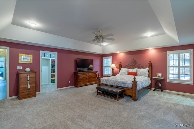 carpeted bedroom featuring a raised ceiling, a ceiling fan, and baseboards