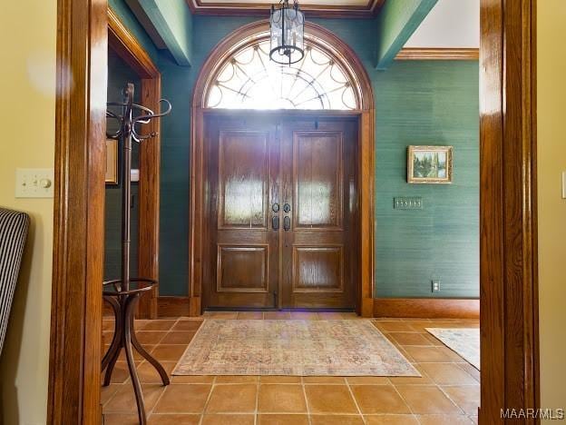 tiled foyer entrance featuring an inviting chandelier and baseboards