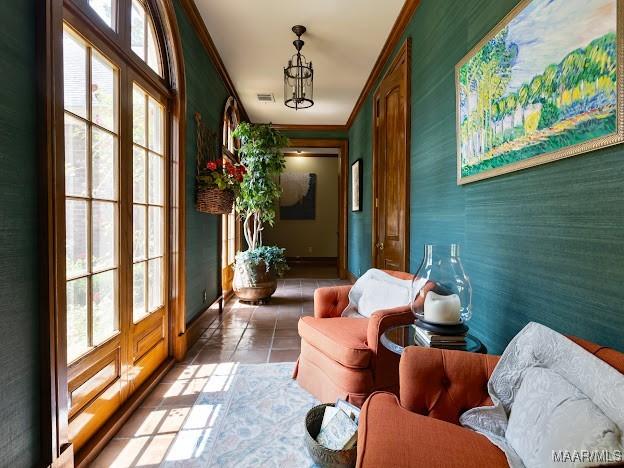 interior space with light tile patterned floors, visible vents, wallpapered walls, baseboards, and ornamental molding