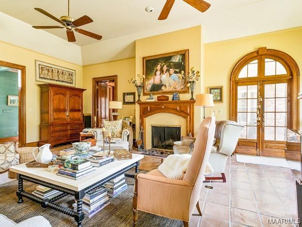 living area featuring light tile patterned floors, vaulted ceiling, a fireplace, french doors, and a ceiling fan