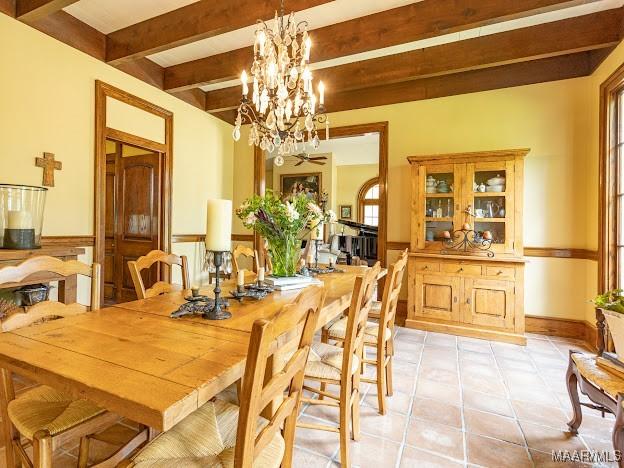 dining space featuring light tile patterned floors, wainscoting, beam ceiling, and a chandelier