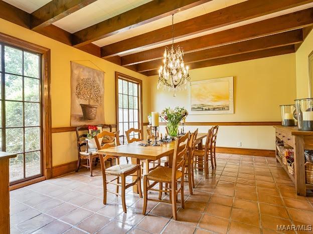 tiled dining space with beam ceiling, an inviting chandelier, plenty of natural light, and baseboards