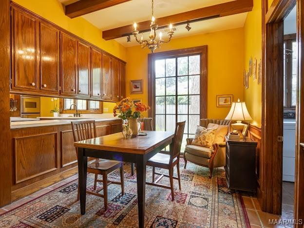 tiled dining space with washer / clothes dryer, beamed ceiling, an inviting chandelier, and a sink