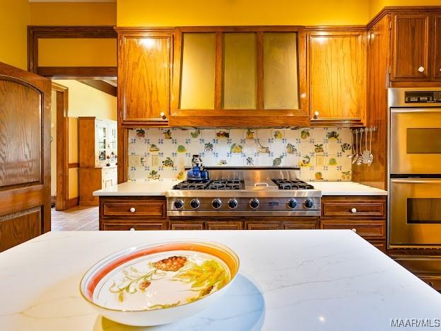 kitchen with brown cabinetry, stainless steel appliances, and decorative backsplash