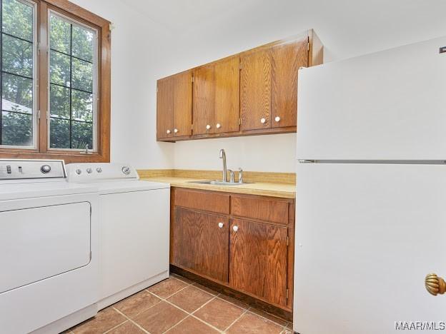 laundry room featuring light tile patterned floors, a sink, independent washer and dryer, and laundry area