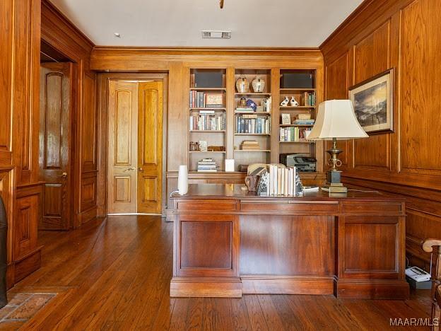 office with wood walls, ornamental molding, visible vents, and built in features