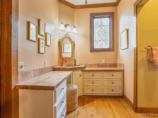 bathroom with wood finished floors, ornamental molding, and vanity