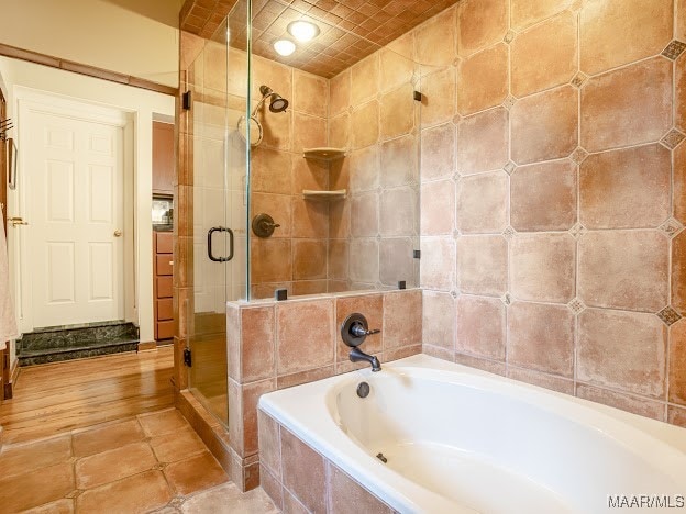 bathroom with shower with separate bathtub, tile patterned floors, and tile walls