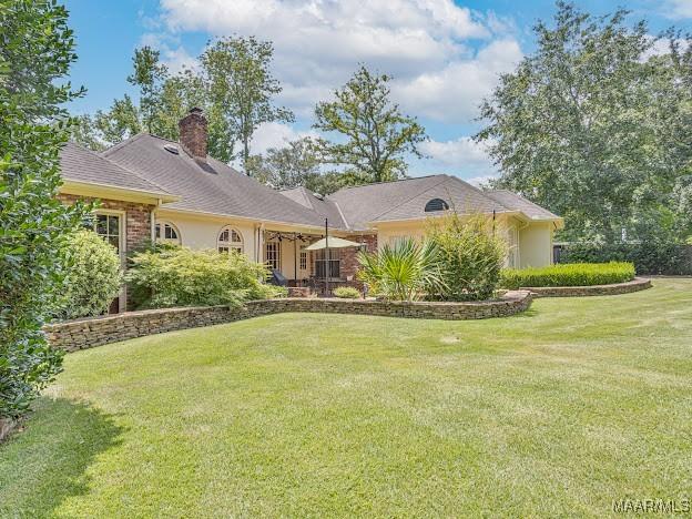 rear view of property featuring a lawn and a chimney