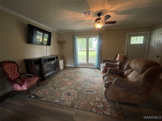 living room featuring ornamental molding, ceiling fan, hardwood / wood-style floors, and a textured ceiling