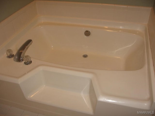 interior details with a tub and tile patterned flooring