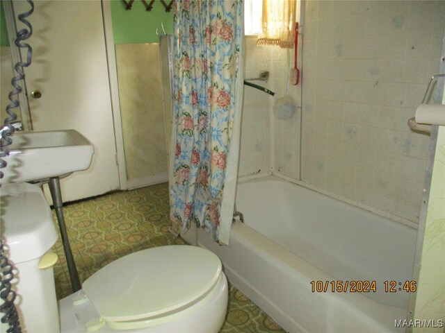 full bathroom with shower / tub combo with curtain, sink, and toilet