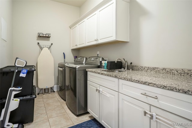 laundry room featuring light tile patterned floors, separate washer and dryer, cabinets, and sink