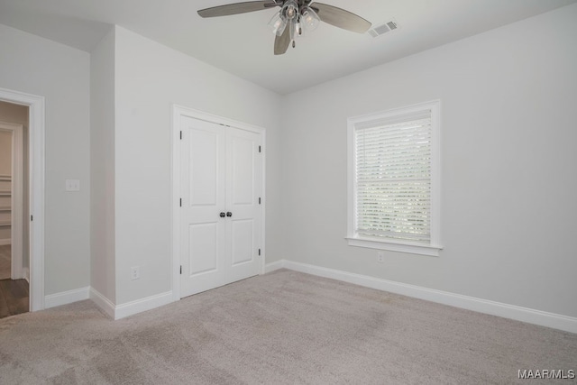 unfurnished bedroom featuring light carpet, a closet, and ceiling fan