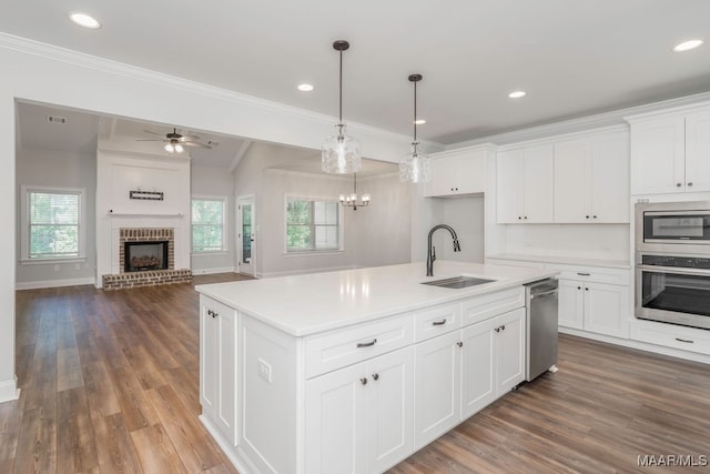 kitchen featuring dark hardwood / wood-style flooring, a center island with sink, sink, appliances with stainless steel finishes, and white cabinetry