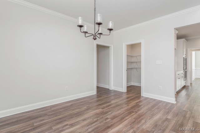 unfurnished room featuring crown molding, hardwood / wood-style floors, and a chandelier