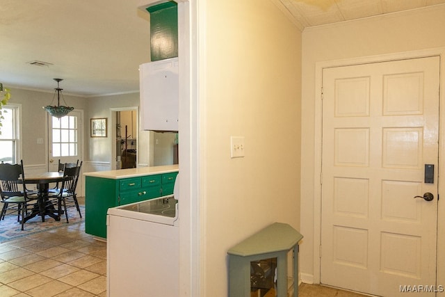 kitchen featuring hanging light fixtures, light tile patterned floors, ornamental molding, white stove, and green cabinets