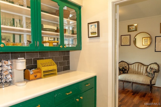 bar featuring green cabinets, crown molding, dark wood-type flooring, and decorative backsplash