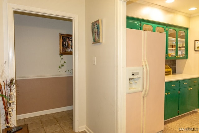 interior space featuring ornamental molding, light tile patterned floors, white fridge with ice dispenser, green cabinets, and decorative backsplash