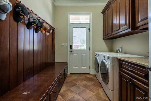 washroom with ornamental molding, washing machine and dryer, and cabinets