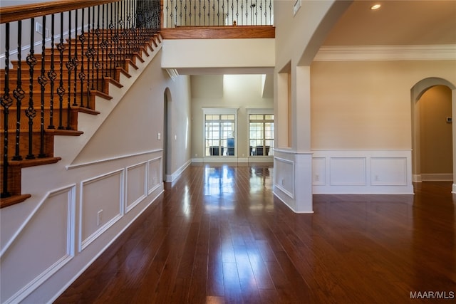 foyer entrance with a towering ceiling, ornamental molding, and dark hardwood / wood-style floors