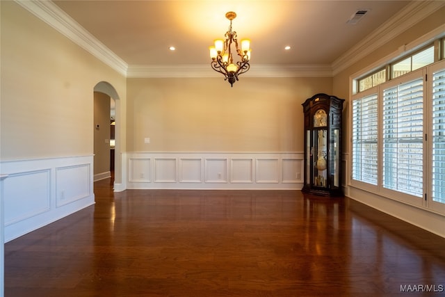 empty room with dark wood-type flooring, ornamental molding, and a chandelier