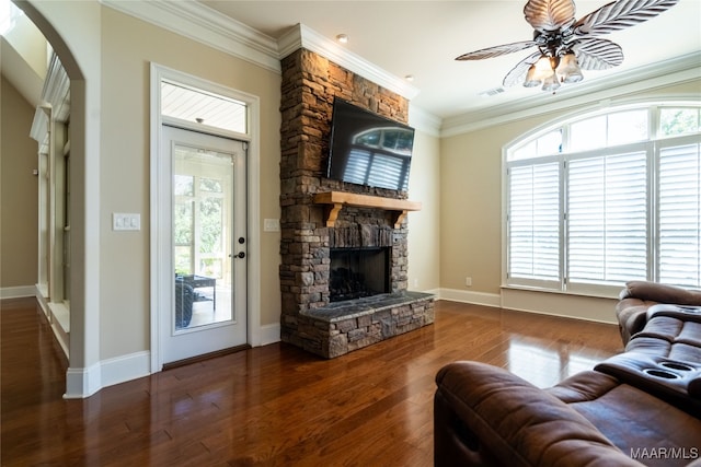 living room with a stone fireplace, crown molding, dark hardwood / wood-style floors, and a healthy amount of sunlight