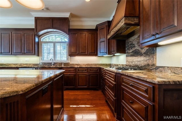 kitchen featuring appliances with stainless steel finishes, premium range hood, dark hardwood / wood-style floors, crown molding, and light stone counters